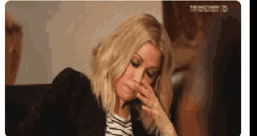 a woman is sitting at a table with her hand to her face .