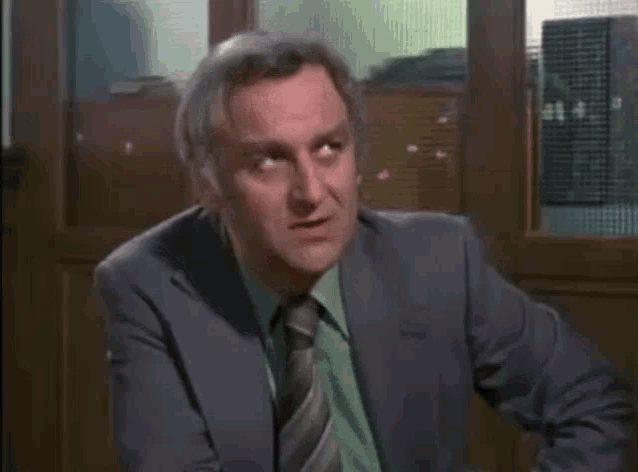 a man in a suit and tie sitting in front of a glass door