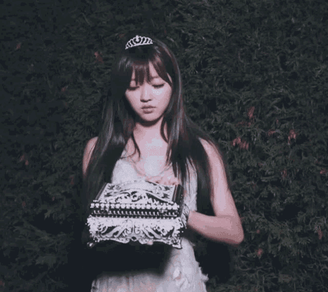a woman in a white dress is opening a silver box