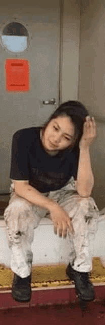 a woman in a black shirt and white pants is sitting on a staircase .