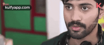 a man with a beard is wearing headphones around his neck .