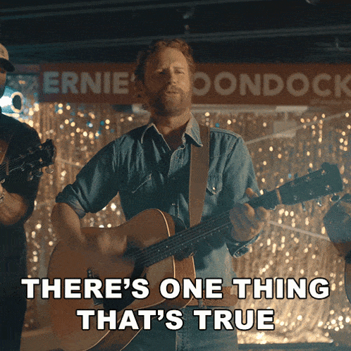 a man playing a guitar with the words there 's one thing that 's true behind him