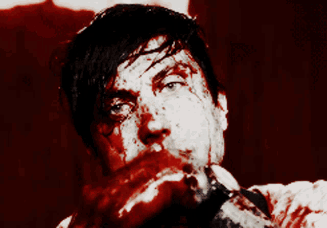 a man with blood on his face is smiling in a dark room