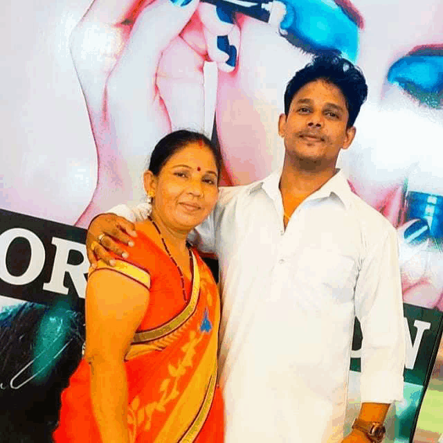 a man and a woman pose for a picture in front of a sign that says or