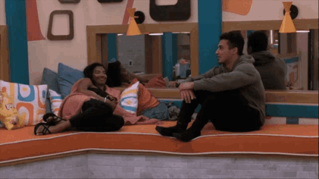 a man and a woman sit on a couch talking