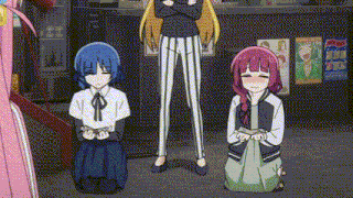 three anime girls are kneeling down in front of a woman standing in a room .