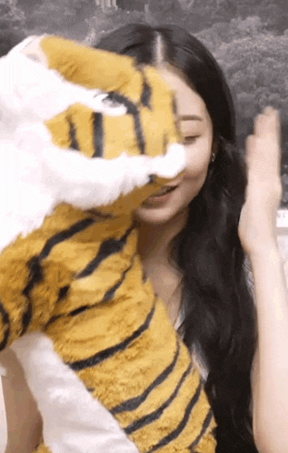 a woman is holding a stuffed tiger in her hands .