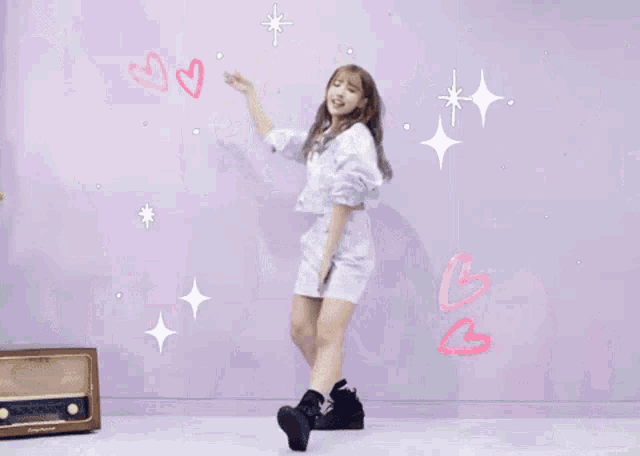 three girls are dancing in front of a purple wall with hearts drawn on them