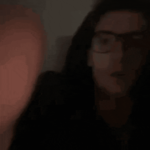 a blurry picture of a man wearing glasses waving his hand