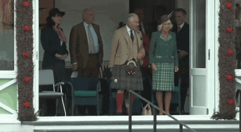 a man in a kilt is standing next to a woman in a green dress