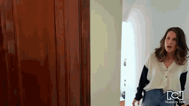 a woman is standing in front of a door with nuestra tele written on the bottom