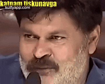 a man with a beard and mustache is looking at the camera .