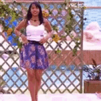 a woman in a blue skirt is standing in front of a pool .