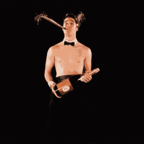 a shirtless man in a tuxedo is holding a bottle of wine over his head .