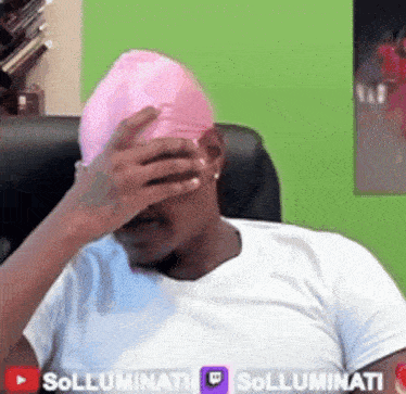 a man wearing a white shirt and a pink hat covering his face