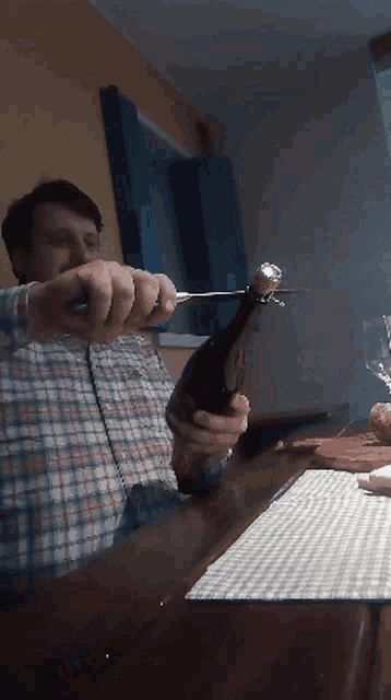 a man is opening a bottle of wine with a knife