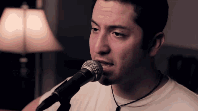 a man singing into a microphone while wearing a white shirt