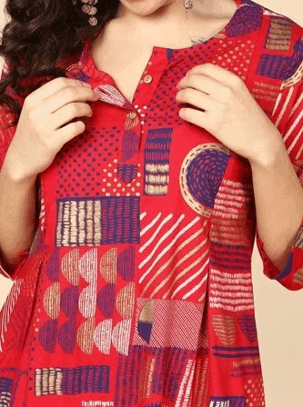a woman is wearing a red dress with a pattern on it and buttons on the front .