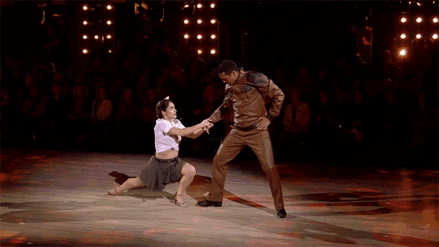 a man and a woman are dancing on a stage with a crowd watching