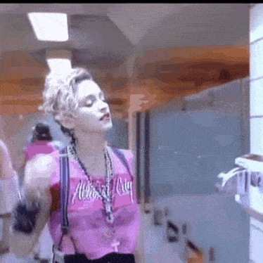 a woman in a pink tank top is standing in a hallway .