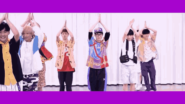 a group of young men are standing in front of a white curtain with their hands in the air