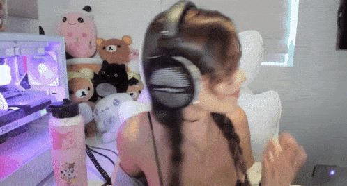 a woman wearing headphones in front of stuffed animals and a computer