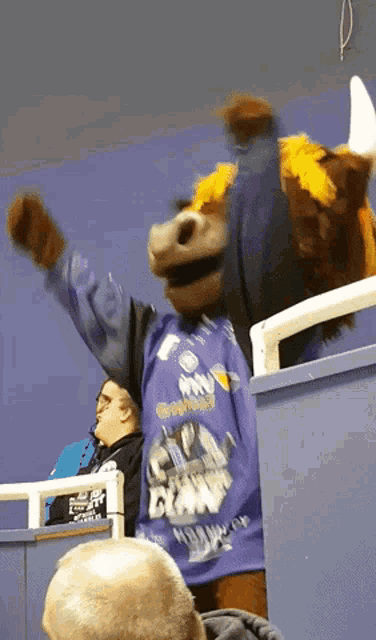 a mascot in a purple shirt that says claw