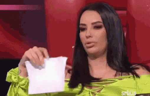 a woman in a neon green top is holding a piece of paper .