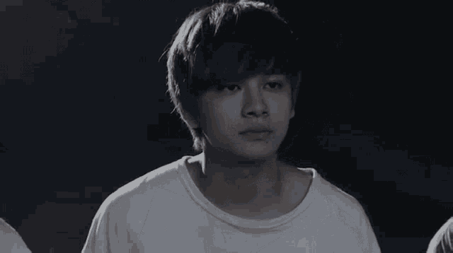 a black and white photo of a young man with blonde hair making a sad face .