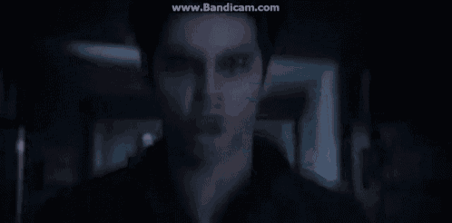 a man is standing in a dark room looking at the camera .