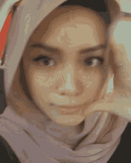 a close up of a woman wearing a hijab and making a face .