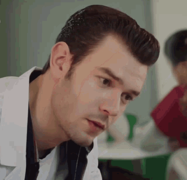 a close up of a man 's face wearing a white coat