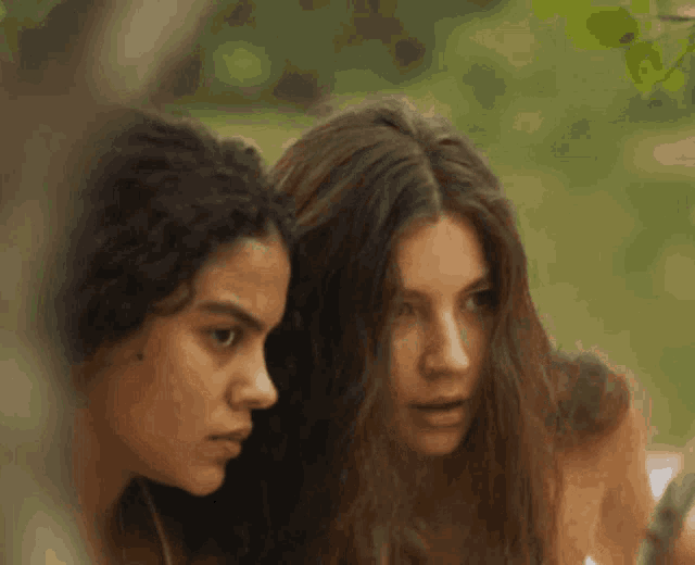 two women with long hair are standing next to each other and looking at something