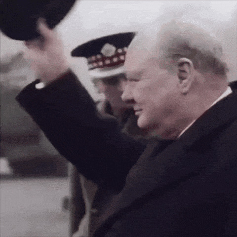 a man in a suit is waving his hat in front of a man in a hat .