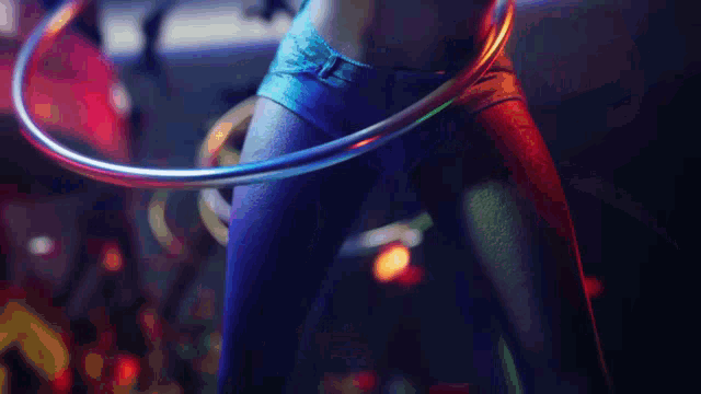 a woman wearing blue shorts is holding a hula hoop around her waist