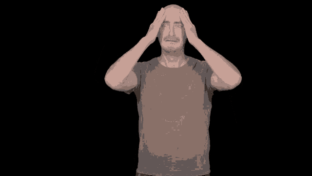 a bald man in a grey shirt is raising his fist