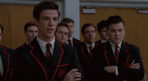 a group of young men in suits and ties are standing in a room