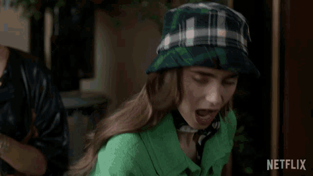 a woman wearing a green jacket and a plaid hat with netflix written on the bottom right