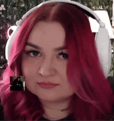 a woman with red hair wearing white headphones looks at the camera
