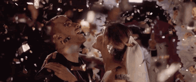 a bride and groom are kissing in front of confetti falling