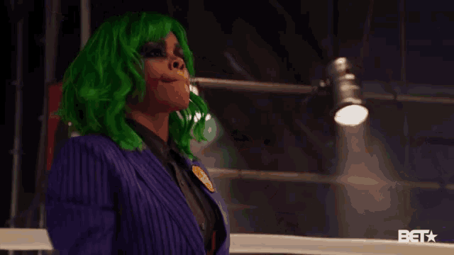 a woman with green hair is standing in a boxing ring with a bet logo in the background