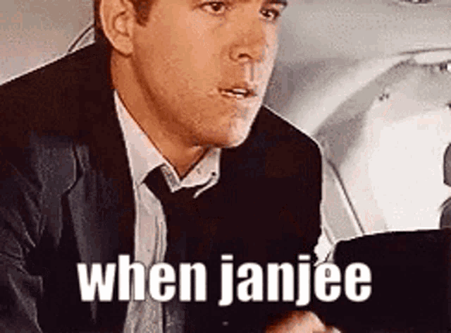 a man in a suit and tie is holding a cell phone and says when janjiee .