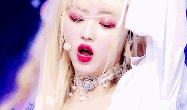 a woman with blonde hair and red lipstick is wearing a white hoodie