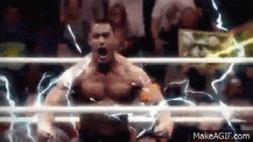 a man is standing in a wrestling ring with lightning coming out of his chest .