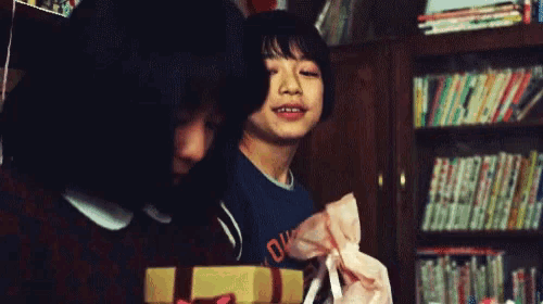 a girl in a blue shirt with the letter o on it holds a gift