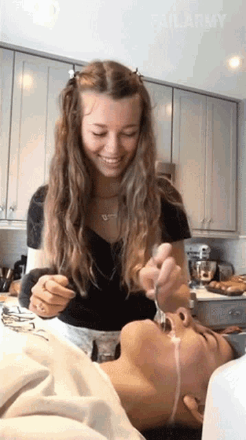 a woman is feeding a man with a fork in a kitchen .