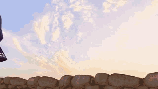 a girl in a sailor outfit is standing on a rock wall
