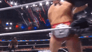a man is wrestling another man in a wrestling ring while a crowd watches .