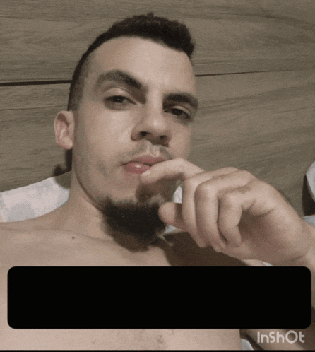 a man with a beard is laying on a bed with his hand on his mouth