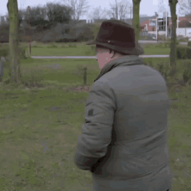 a man wearing a hat throws it in the air with the word kende behind him